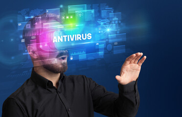 Businessman looking through Virtual Reality glasses with ANTIVIRUS inscription, innovative security concept