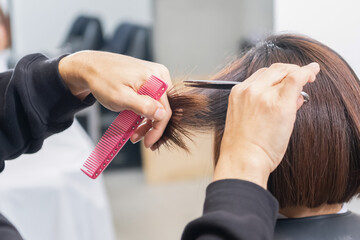 Naklejka premium ヘアサロンで髪の毛をカットする美容師の手元