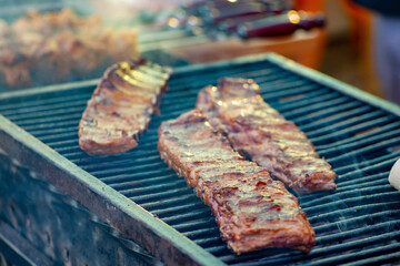 Ribs are turned over on the grill. BBQ ribs. Street food.