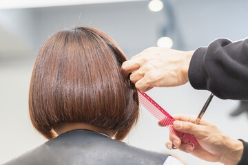 Fototapeta premium ヘアサロンで髪の毛をカットする美容師の手元