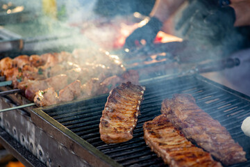 Ribs are turned over on the grill. BBQ ribs. Street food.