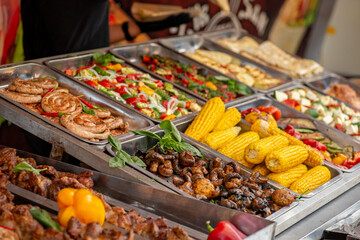 Trays filled with food at the food court. Street food. Grilled vegetables and meat.