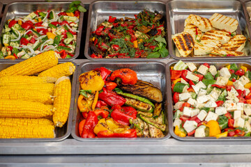 Trays filled with food at the food court. Street food. Grilled vegetables and meat.