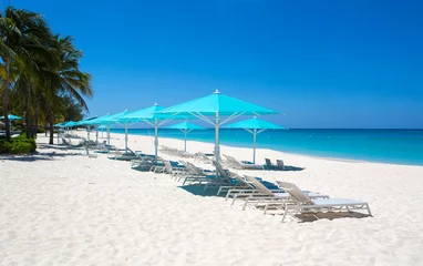 Photo sur Plexiglas Plage de Seven Mile, Grand Cayman Grand Cayman Beach Chaises longues Parasols bleus au bord de l& 39 eau.Caraïbes, Grand Cayman, Seven Mile Beach, îles Caïmans, palmiers. Plage vide, pas de touristes