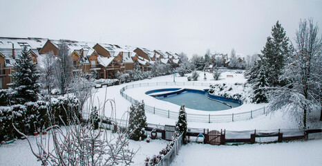 Snow covered yard with a pool in a beautiful neighborhood in Bucharest. Christmas background. Cold temperature, winter time