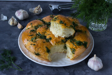 Garlic buns on a white plate on a gray marble background