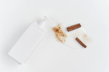 white cosmetic container on a white background with spilled white contents with cinnamon