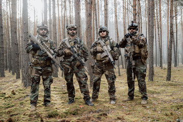 Fototapeta premium Portrait of a middle-aged bearded soldiers in a Woodland military uniform and helmet, with headphones on his head holding a rifle.