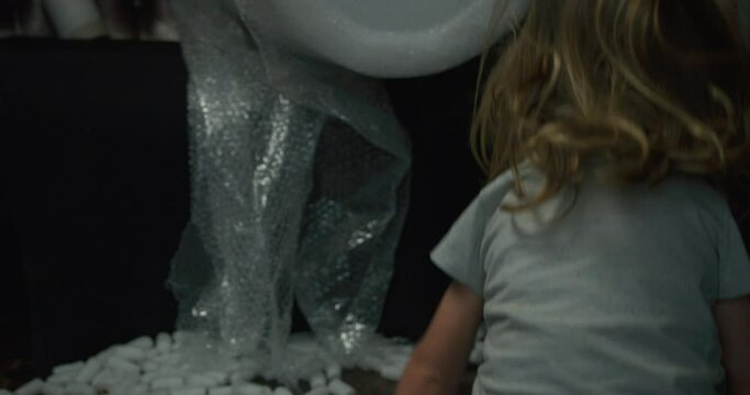 A little preschooler is playing with the styrofoam packaging at home from a house move