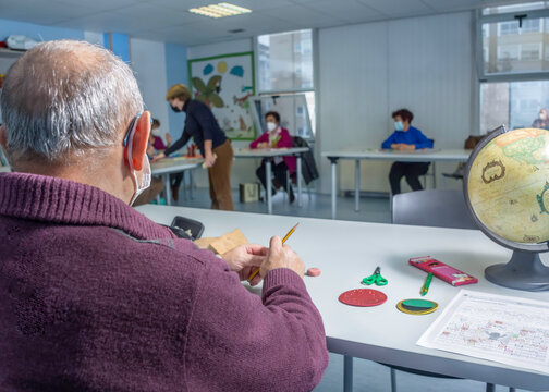 Retired Man Attending Class In Community Center. Wearing Face Masks. Social Distance And Safety In Classroom.  Teacher With Senior Students