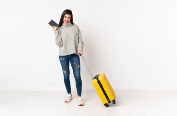 A full length body of a traveler woman with a suitcase over isolated white wall