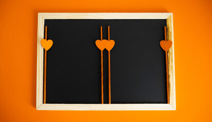 Blackboard with copy space decorated with orange hearts.