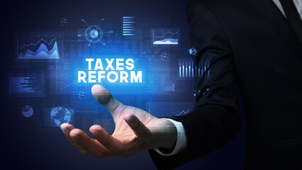 Hand of Businessman holding TAXES REFORM inscription, business success concept