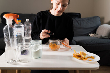 Millennial girl doing diy cleaning spray at home with vinegar, soda and lemon. Zero waste sustainable lifestyle. Environmentally friendly home. Spring cleaning 