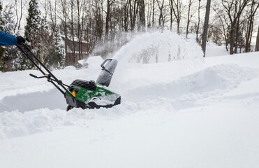 Snow blower in action clearing a residential driveway after snow storm