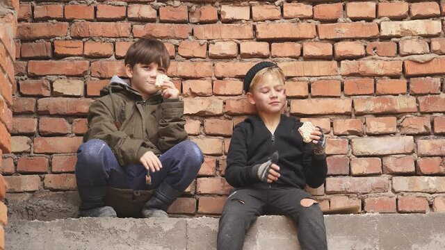 Poor street kids enjoy meal on street, eating donationa food. Social issues, poverty problem concept.