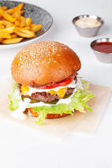 Single tasty burger with french fries and sauces