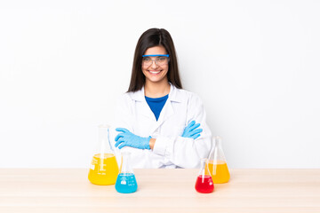 Young scientific woman in a table keeping the arms crossed in frontal position