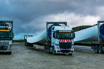 Several trucks of special transport parked transporting wind turbine blades.