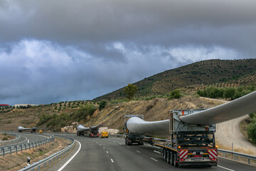 Several special transport trucks on the road transporting wind turbine blades. - obrazy, fototapety, plakaty