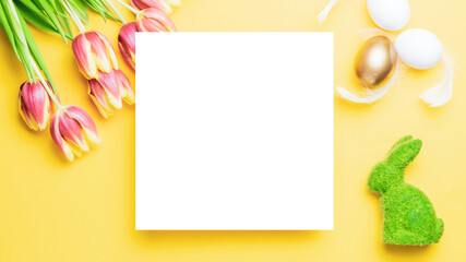 Easter tulips. Golden, white colour egg in basket with spring tulips, feathers on pastel yellow background in Happy Easter decoration. Traditional design in top view.