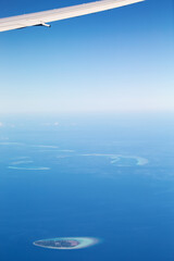 Fototapeta na wymiar Window view from airplane on wing and maldivian atoll with islands. Aerial shot