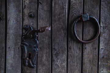 old wooden door, fragment of a vintage wooden door with an iron ring, cracks and scratches, cracked...