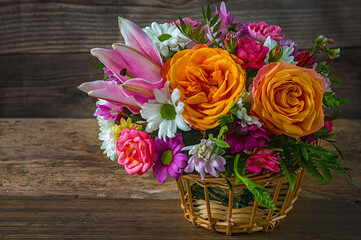 bouquet of flowers drops in a wicker basket on a wooden table close up side view rustic style