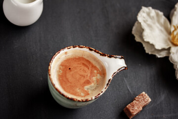 Ceramic coffee mug with coffee with milk or latte, sugar cubes on dark background. Flat lay, top view.