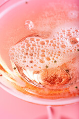 Fototapeta premium Closeup of glass with sparkling rose wine on pink background