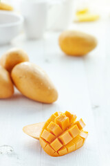 Fresh ripe yellow sliced diced mango on white wooden table