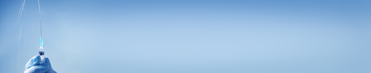 Doctor in blue latex gloves fill in syringe with medicine from glass vial. Long banner