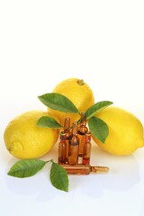 Vitamin C injection.A solution of vitamin C in brown glass ampoules set, lemons with green leaves on a white background with reflection. ampoules and Serum with Vitamin C. Organic cosmetics. 