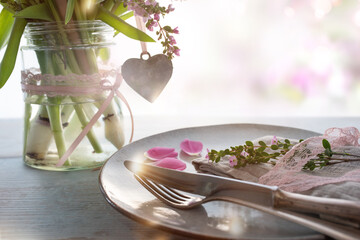 Table dekoration for a mothers day menu. Spring flowers with heart shape on gray wooden table and...
