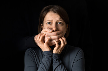 Violence concept. A man's hand closes a woman's mouth.