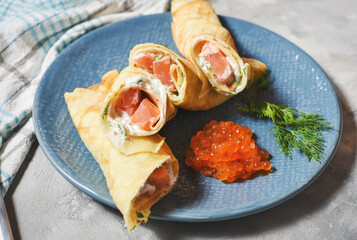 Delicious breakfast - crepes with smoked salmon, sour cream and caviarch on concrete background