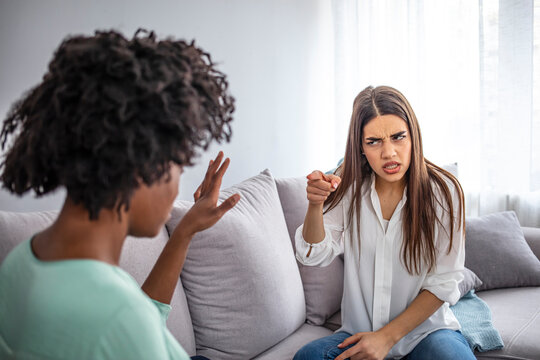 Girls Quarrel. Women Talking Loudly About Something. Friends Arguing On Sofa At Home. Two Female Friends Arguing With Each Othe.  Friendship, Quarrel, Female Disagreement, Copy Space