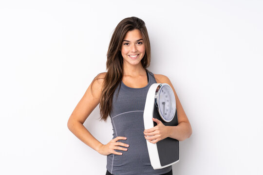 Teenager Brazilian girl holding a scale over isolated white background with weighing machine