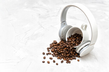 Roasted coffee beans and wireless headphones on a concrete table