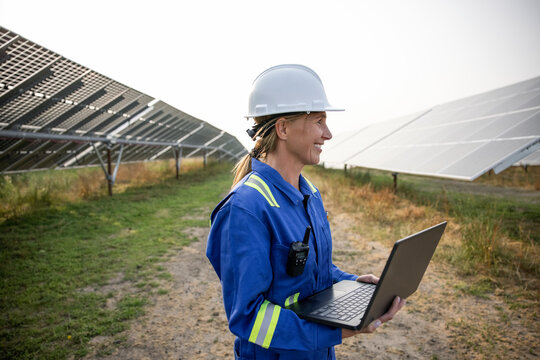 Technician carrying laptop in solar farm