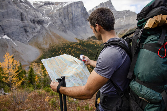 Male backpacker with map and compass in mountains, Canadian Rockies
