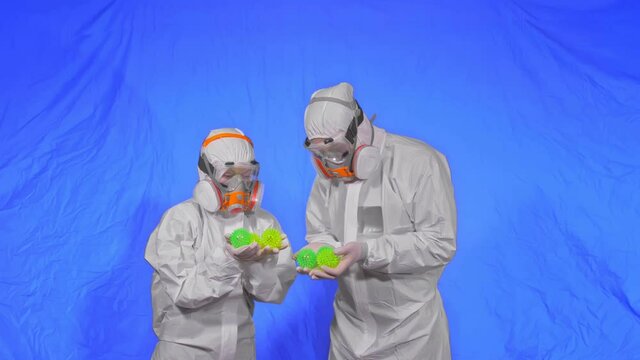 Doctor in respirator show a virus model concept health safety protection coronavirus epidemic 2019 nCoV. Slow motion. Health worker wearing protect medical aerosol spray paint mask. Green ball spike.