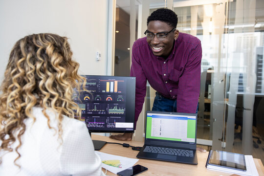 Happy Business People Talking At Computer And Laptop In Office