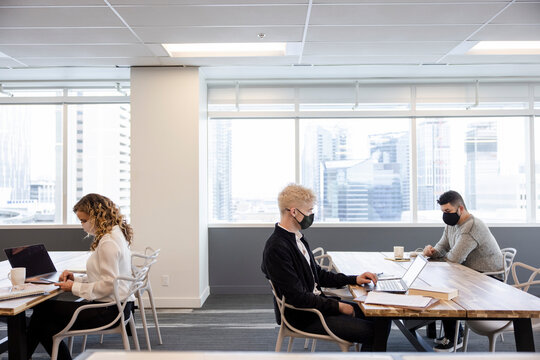 Business People In Face Masks Working At Distance In Coworking Space