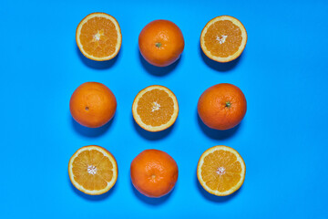 Whole and split oranges on a blue background. CITRUS CITRIC
