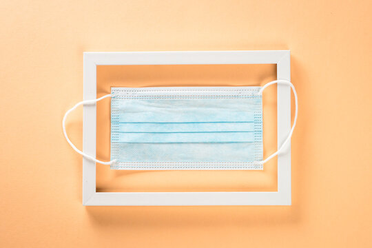 Photo frame and face mask at pastel background. Creative layout.