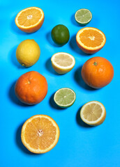 Whole and split oranges, limes and lemons with skin on a blue background. CITRUS CITRIC