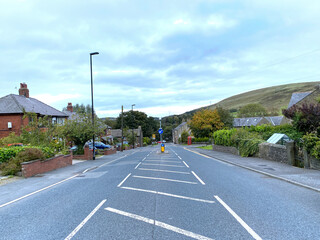 Fototapeta premium Looking down the, A672 road, with houses, cars, and hills in the distance in, Oldham, Lancashire, UK