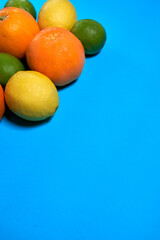 Whole oranges, limes and lemons with skin on blue background. CITRUS CITRIC
