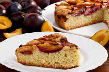 slice of pie with plums on a table against a background of plums